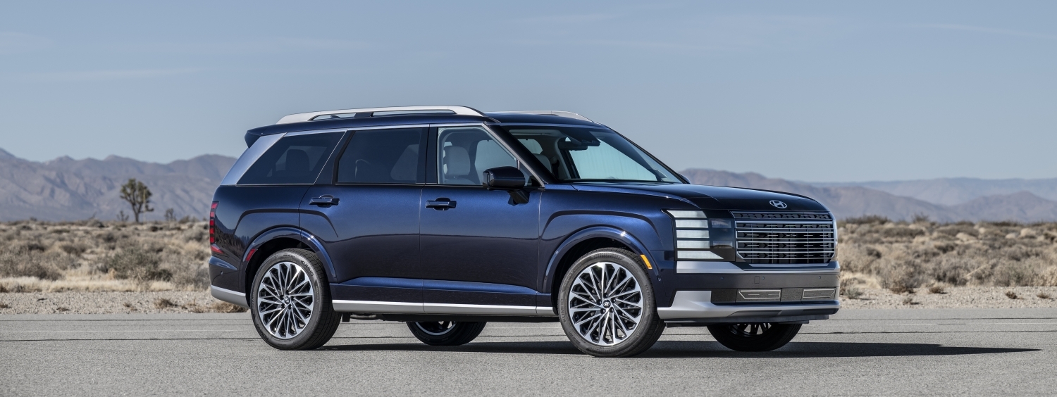 2026 Hyundai Palisade three-row SUV in deep navy blue, parked on an open road with desert mountains in the background — available at Chico Hyundai